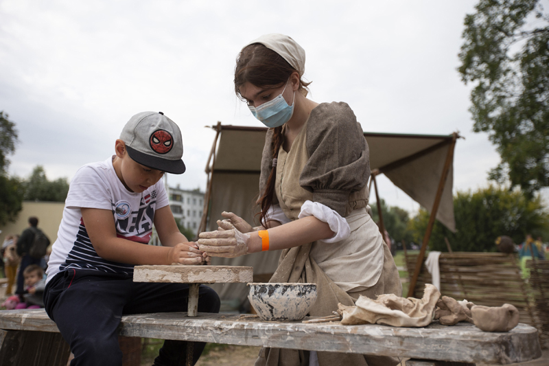 A staff member helps a young visitor with pottery at a cultural event on 873rd Moscow City Day