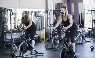 People wearing face masks exercise at a reopened fitness club in Barrie