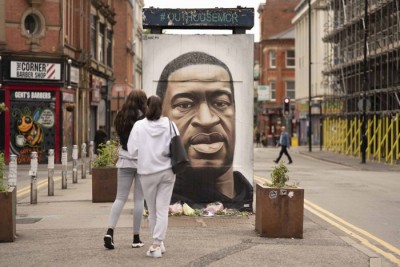 People gather by a mural of George Floyd in UK's Manchester