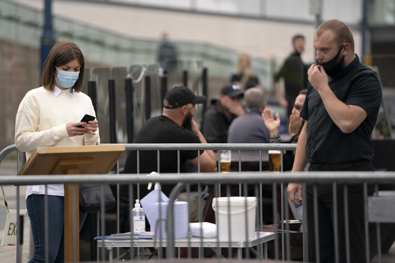 A woman uses the track and trace app at a pub in Manchester