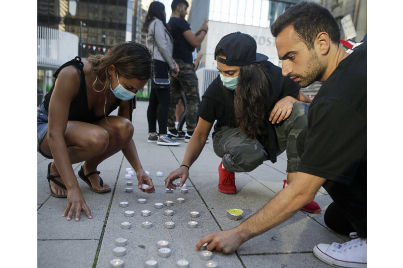 Participants arrange candles during a vigil in front of the Vancouver Art Gallery