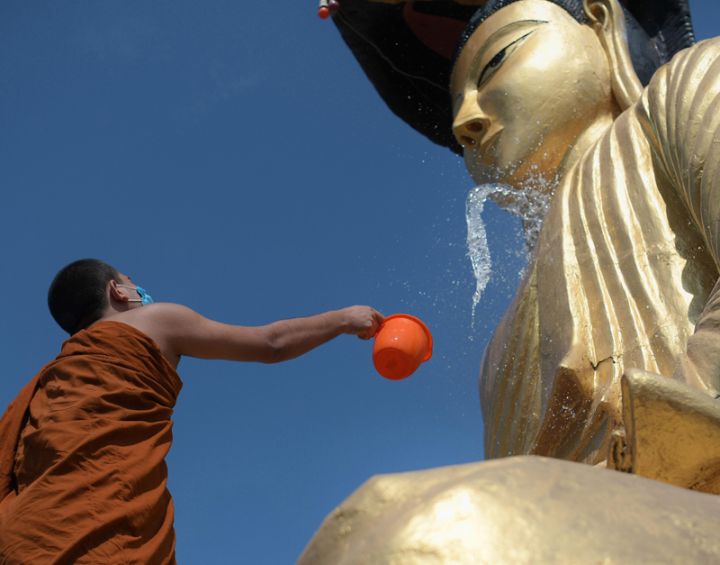 Buddhist monk cleaning statue of Lord Buddha at Agartala monastery